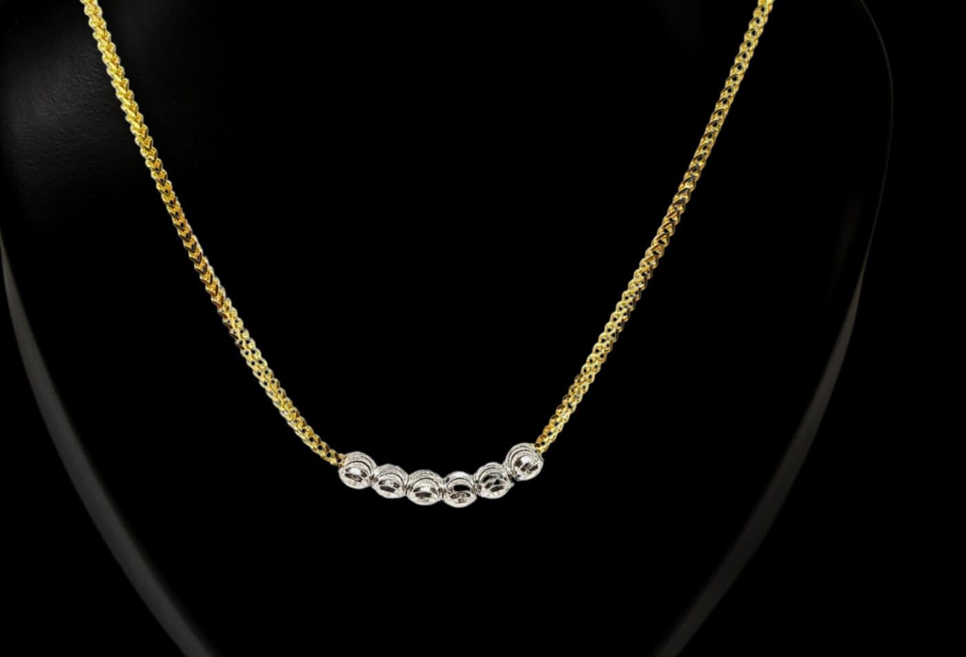 A yellow gold chain with a row of white-gold beads at the centre