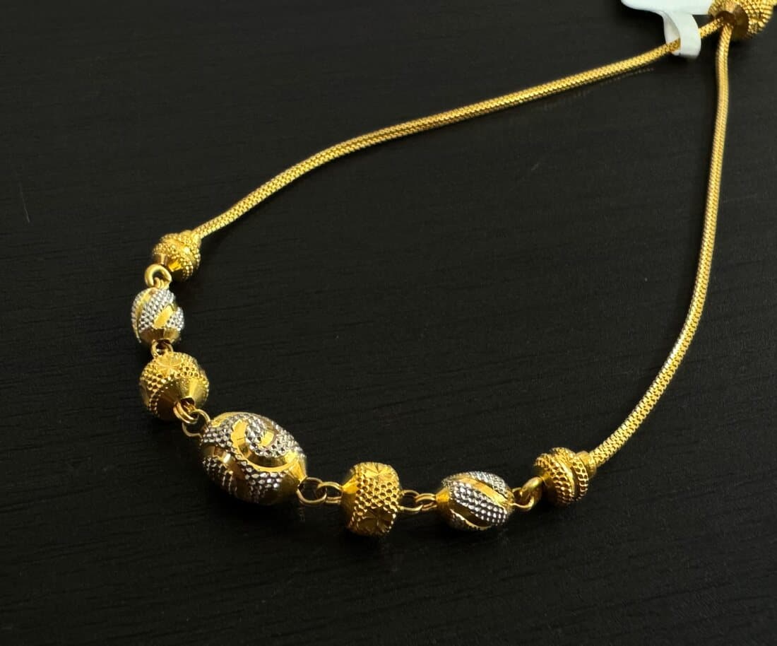 A 22ct gold adjustable bracelet with yellow and white-gold beads