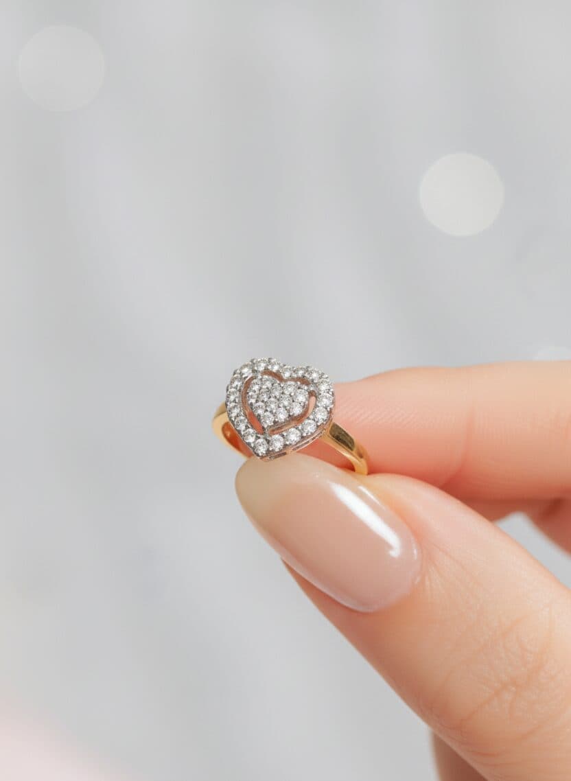 A heart-shaped diamond halo ring held between two fingers