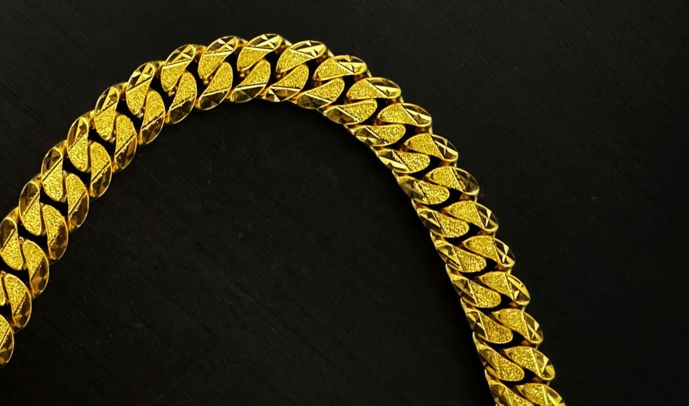 A 22ct gold curb bracelet with textured and diamond-cut links, on black
