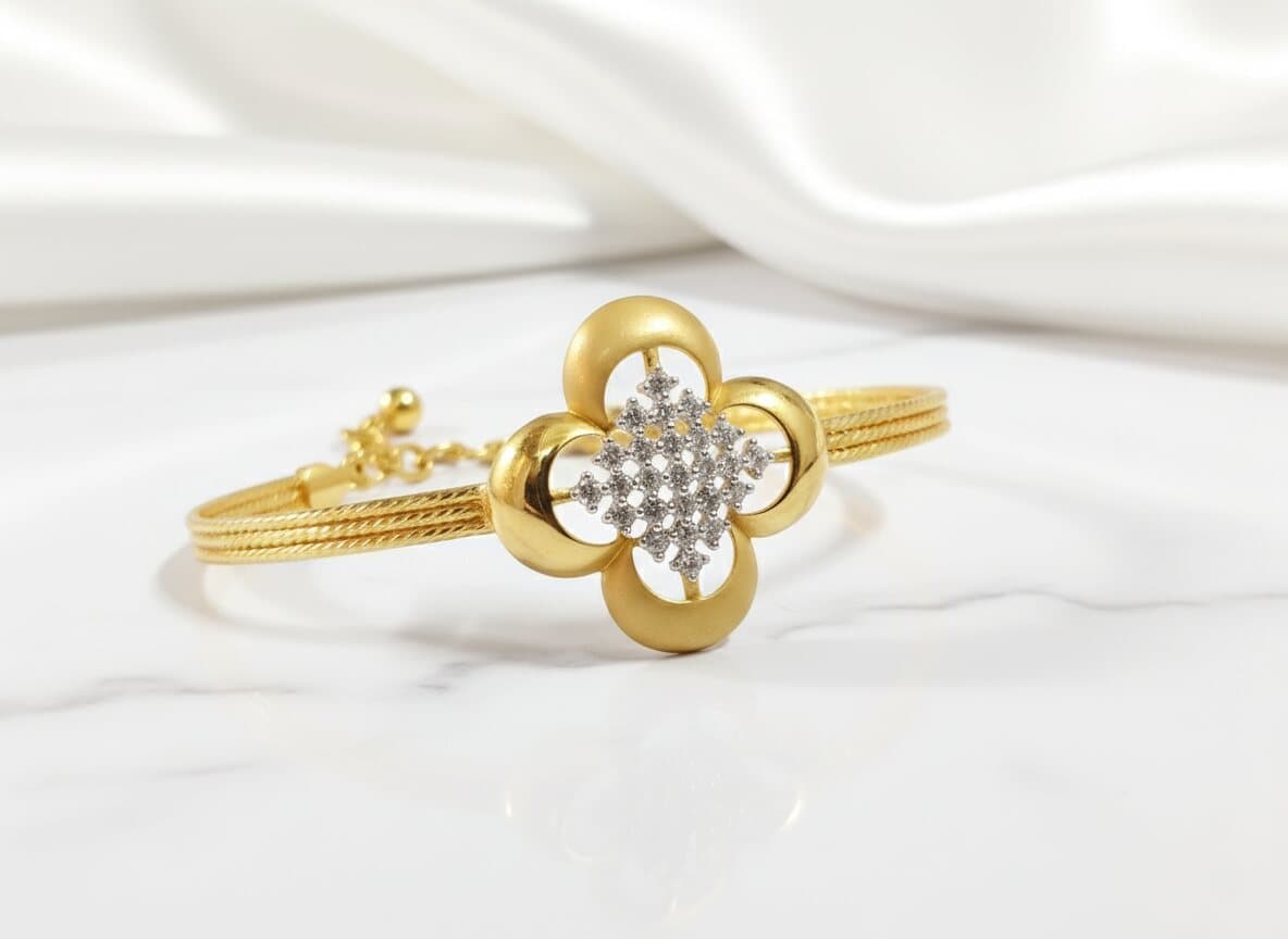 A gold bracelet with a four-petal flower of matte and polished gold around a cluster of white stones