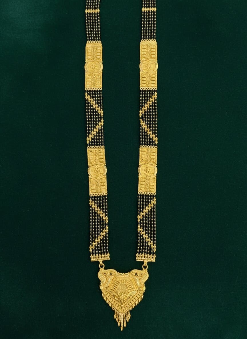 A long 22ct gold mangalsutra with wide black-bead panels, patterned gold blocks and an ornate pendant