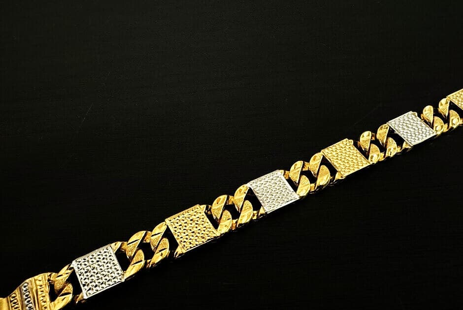 A men's two-tone gold bracelet with curb links and white-gold panels, on black